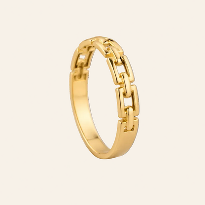 A polished yellow gold ring with a modern geometric chain-link design, standing upright on a light beige background.