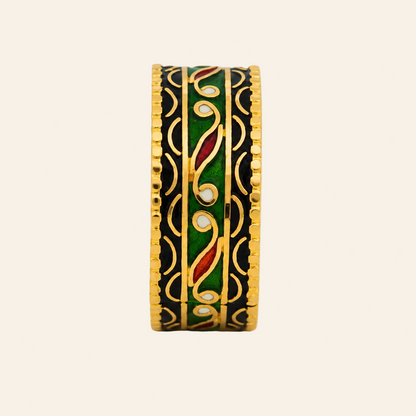 A gold-plated ring with a black enamel background, featuring green, red, and gold floral enameled details, shown on a plain light gray background.