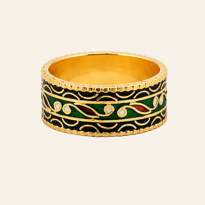A wide gold band ring with black enamel, green enamel, and small red enamel accents, accented with white stone-like details, shown on a white background.
