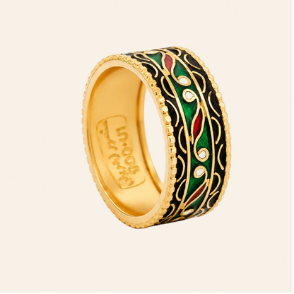 A gold-plated ring with a black enamel background and intricate green, red, and white floral enameled details, shown on a clean white background.